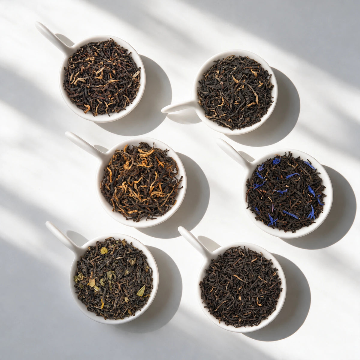 The six loose teas in the Black Tea Sampler Pack, in white bowls
