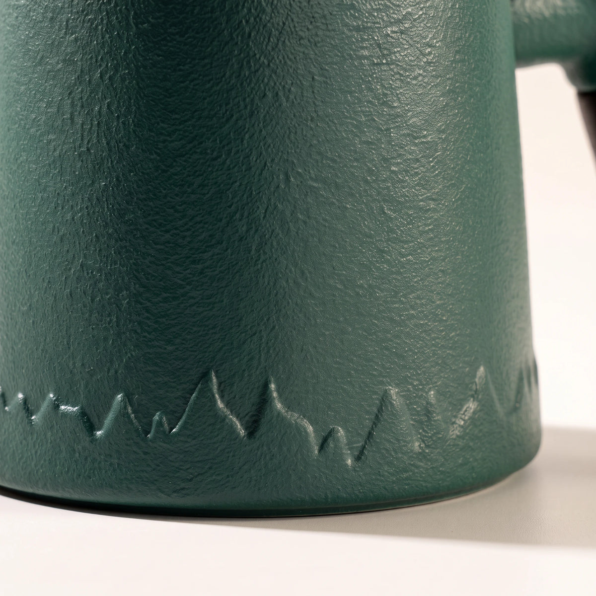Everest ceramic tea infuser mug, Forest Green, close-up of the textured base and mountain pattern