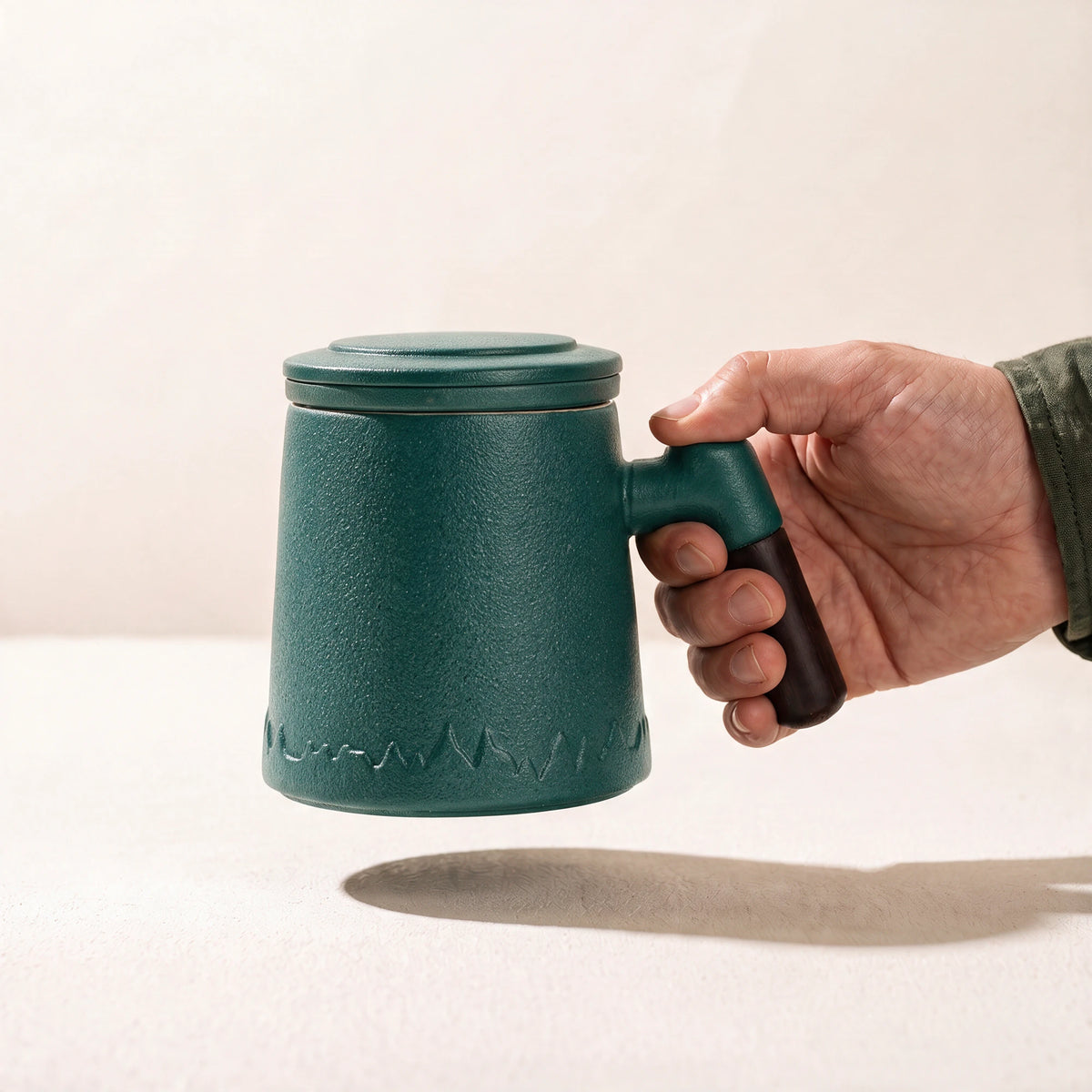 Everest ceramic tea infuser mug, Forest Green, held by the handle