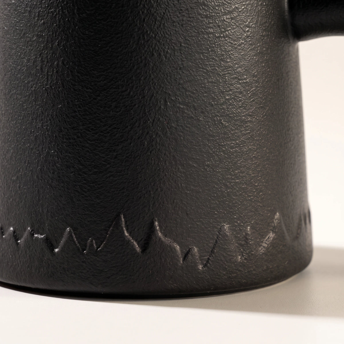 Everest ceramic tea infuser mug, Noir Black, close-up of the textured base and mountain pattern