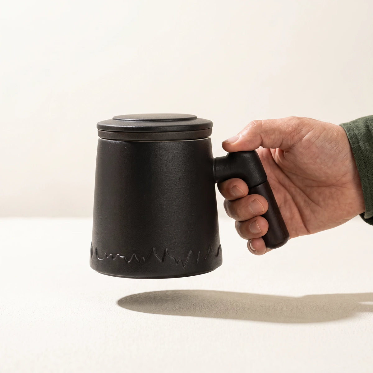 Everest ceramic tea infuser mug, Noir Black, held by the handle