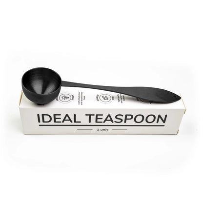 Ideal tea spoon, matte black, resting on its box, on a white background