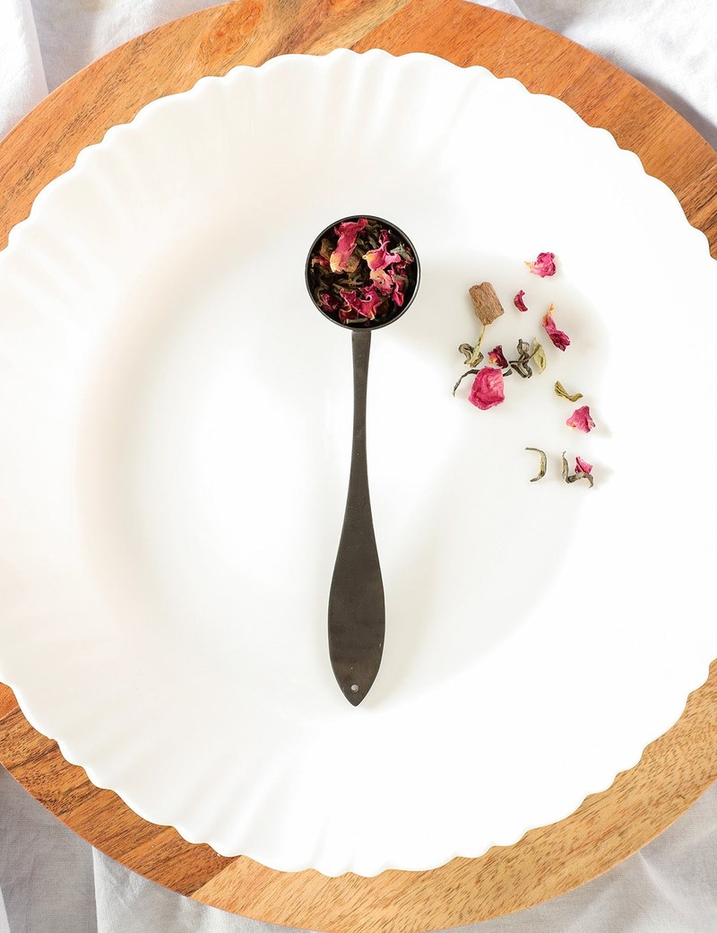 Ideal tea spoon with loose-leaf tea on a white plate