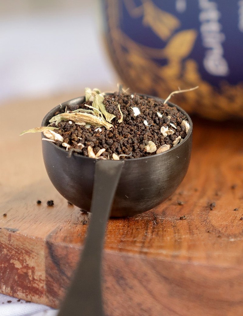 Ideal tea spoon in matte black, holding chai on a wooden board