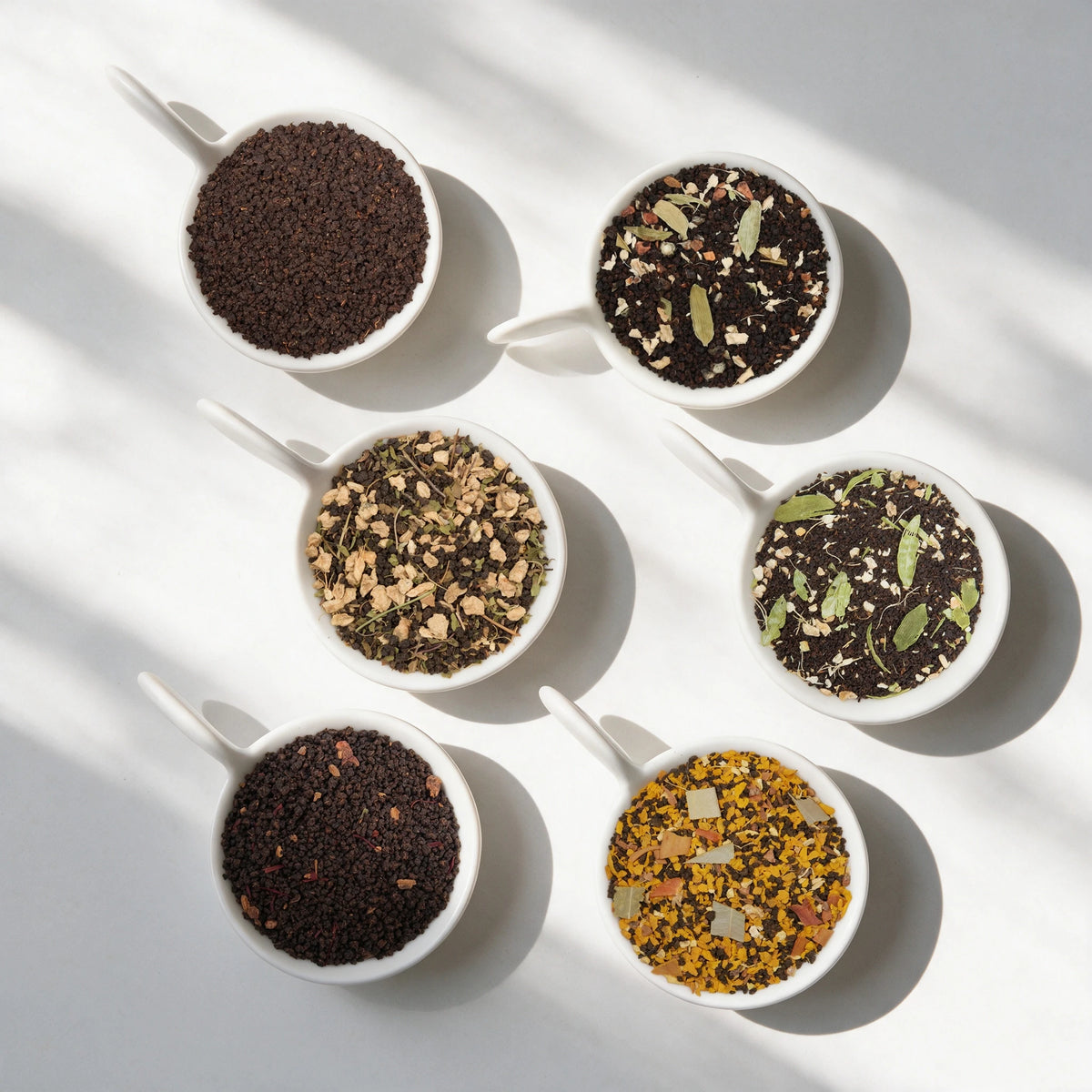 The six loose teas in the Indian Chai Tea Sampler Pack, in white bowls