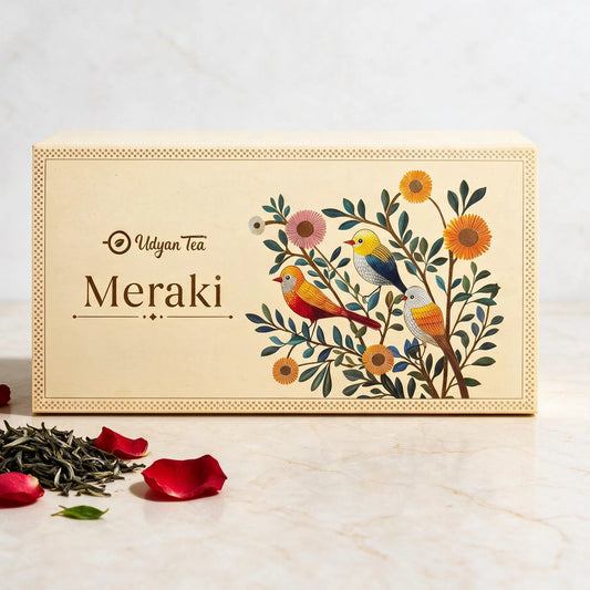 Meraki tea gift box, cream with birds and flowers, beside loose tea and rose petals
