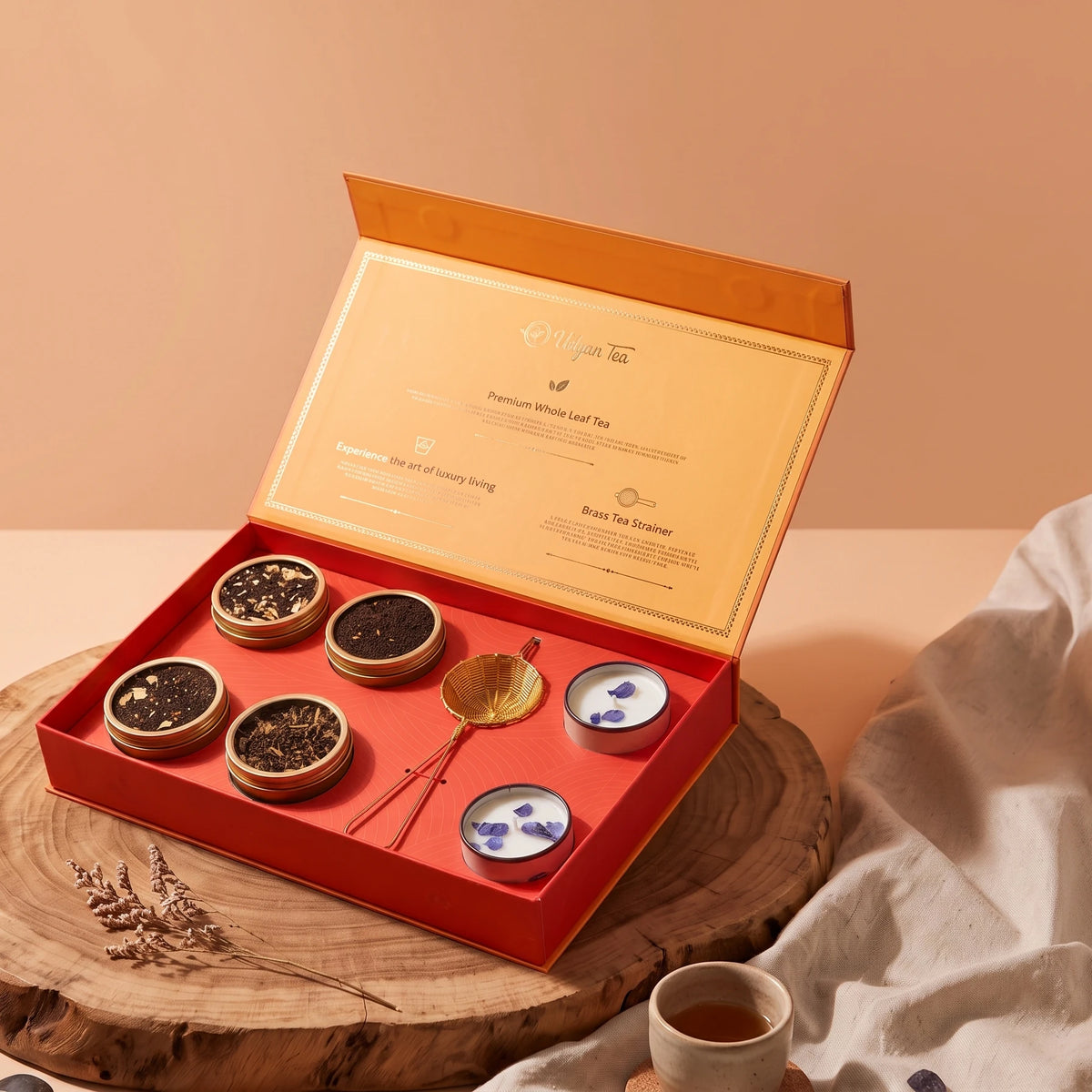Meraki gift box open, with four tins of tea, a brass strainer and two candles