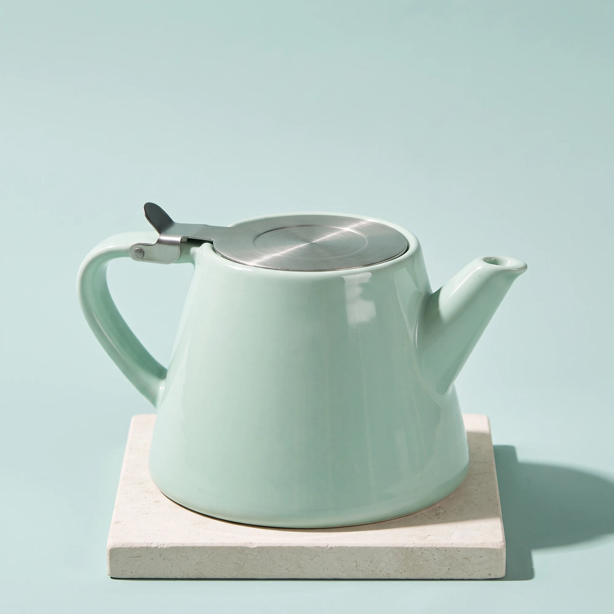 Muse ceramic teapot with infuser, Aqua Blue, on a stone tile