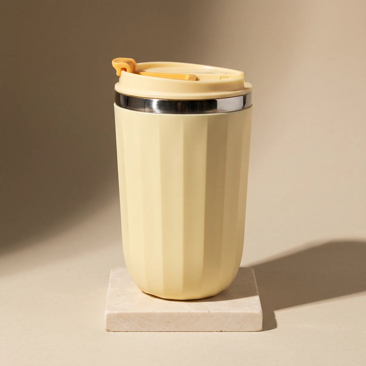 Opal travel tumbler, Honey Yellow, on a stone tile, coloured backdrop