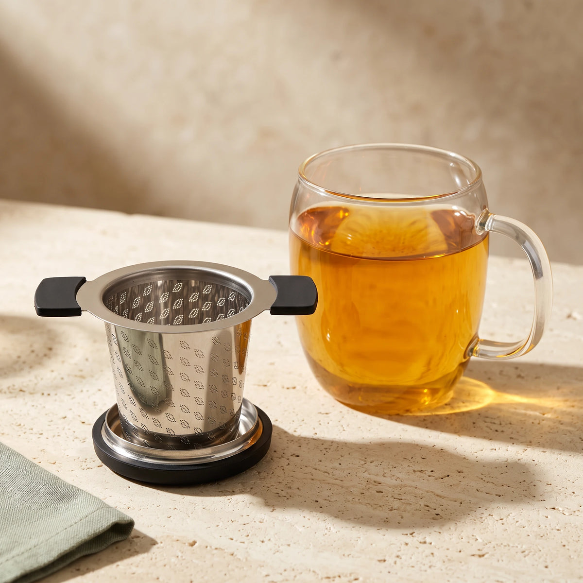 Perfect tea infuser, resting on its lid beside a mug of tea