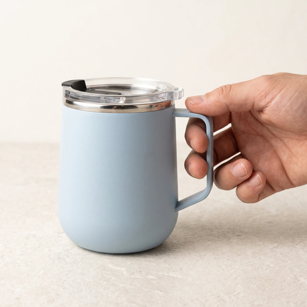 Pulse travel mug, Frost Blue, held by the handle