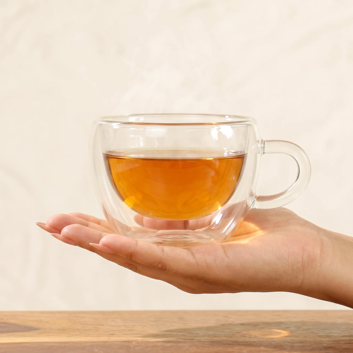 Stellar double wall glass tea cups, with tea, on an open hand