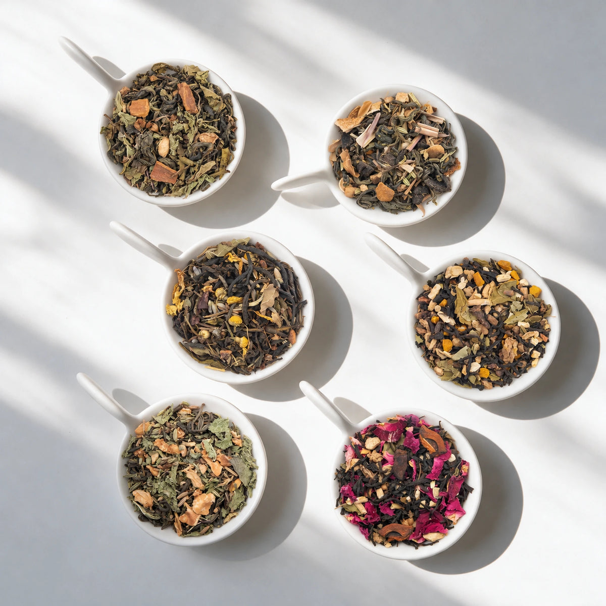 The six loose teas in the Wellness Tea Sampler Pack, in white bowls